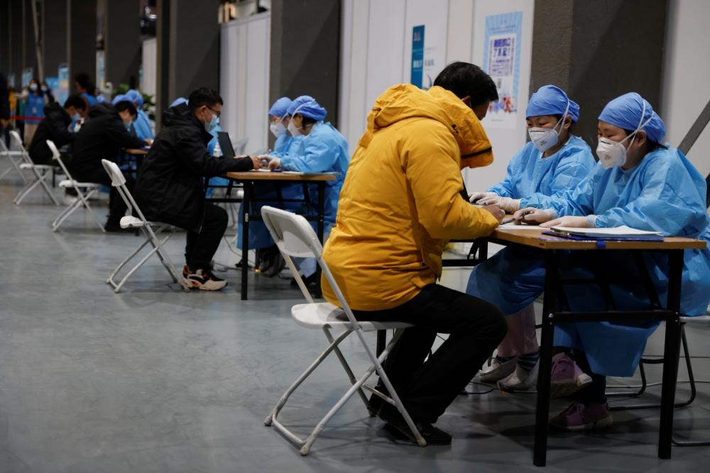 People fill forms before receiving a dose of a coronavirus disease (COVID-19) vaccine at a vaccination site, during a government-organized visit, in Beijing, China January 15, 2021. REUTERS/Carlos Garcia Rawlins