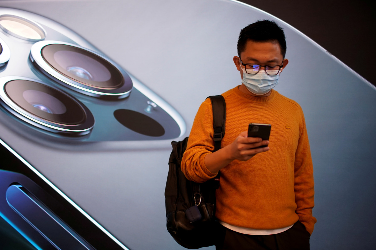FILE PHOTO: A man wears a face mask while waiting at an Apple Store before Apple's 5G new iPhone 12 go on sale, as the coronavirus disease (COVID-19) outbreak continues in Shanghai China October 23, 2020. REUTERS/Aly Song/File Photo
