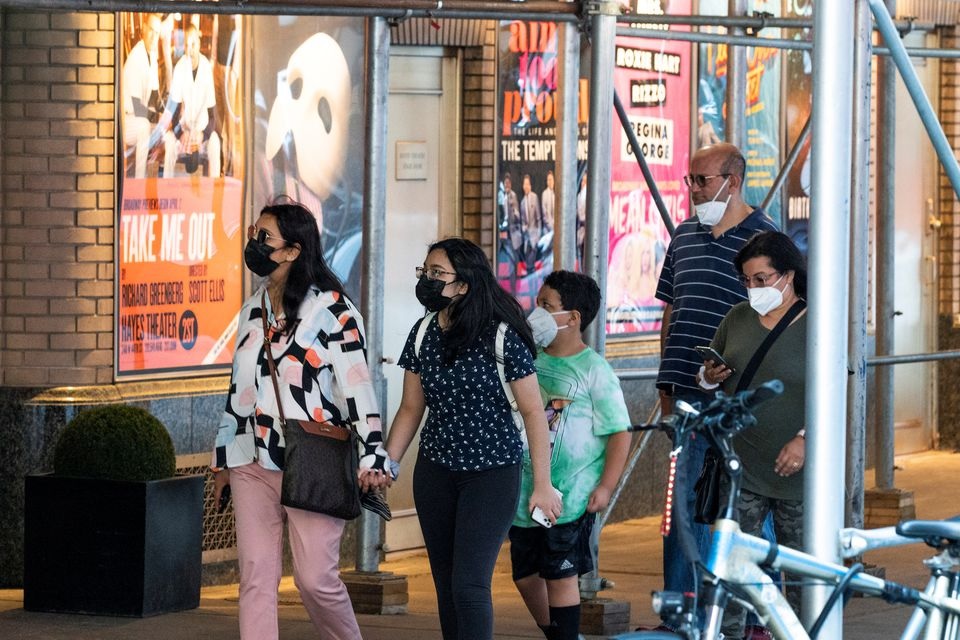 People walk near posters of theatre shows while they wear masks to prevent against the spread of the coronavirus disease (COVID-19), as the highly transmissible Delta variant has led to a surge in infections, in New York City, U.S., July 30, 2021. REUTERS/Eduardo Munoz