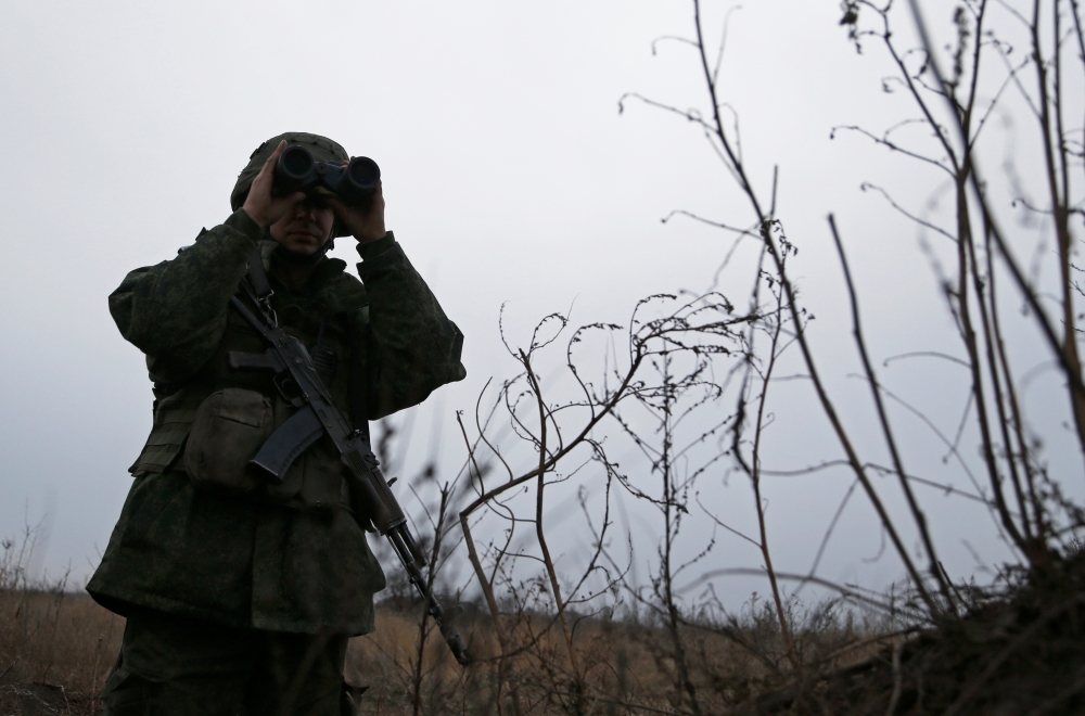A militant of the self-proclaimed Luhansk People's Republic looks through binoculars as he stands guard at fighting positions on the line of separation from the Ukrainian armed forces in the outskirts of Kirovsk in Luhansk Region, Ukraine December 1, 2021. REUTERS/Alexander Ermochenko