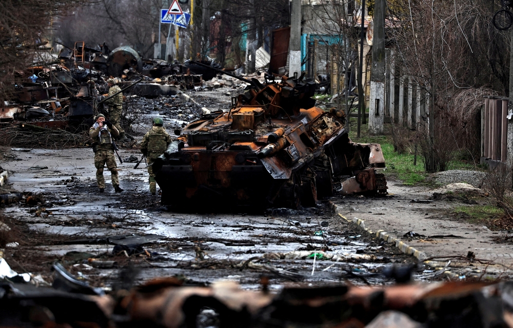 A soldier takes a photograph of his comrade as he poses beside a destroyed Russian tank and armoured vehicles, amid Russia's invasion on Ukraine in Bucha, in Kyiv region, Ukraine April 2, 2022. REUTERS/Zohra Bensemra/File Photo