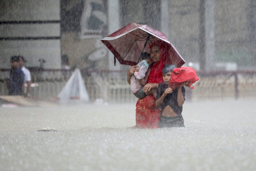 People wade through the water as they look for shelter during a flood, amidst heavy rains that caused widespread flooding in the northeastern part of the country, in Sylhet, Bangladesh, June 18, 2022. Reuters/Abdul Goni 