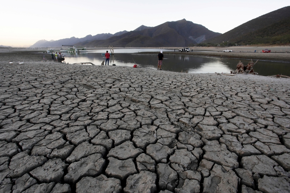 People gather along the dried basin of the La Boca dam as more than half of Mexico faces moderate to severe drought conditions, in Santiago, Mexico. (Reuters/Daniel Becerril/File Photo)