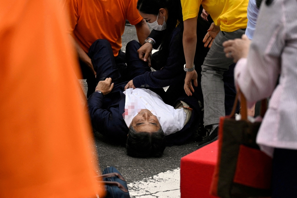FILE PHOTO: Former Japanese Prime Minister Shinzo Abe lies on the ground after he was shot during an election campaign in Nara, western Japan July 8, 2022 in this photo taken by The Asahi Shimbun. Image pixelated at source. The Asahi Shimbun/via REUTERS ATTENTION EDITORS - THIS IMAGE WAS PROVIDED BY A THIRD PARTY. MANDATORY CREDIT. NO RESALES. NO ARCHIVES. JAPAN OUT. NO COMMERCIAL OR EDITORIAL SALES IN JAPAN./File Photo