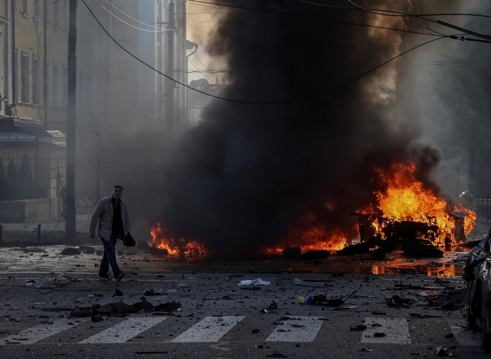 A driver walks near his burned car after Russian military strike, as Russia's invasion of Ukraine continues, in central Kyiv, Ukraine, October 10, 2022. (REUTERS/Gleb Garanich)