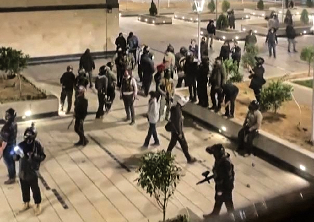 This image grab from a UGC video posted on November 1, 2022, reportedly shows Iranian security forces warning residents in a complex in the Chitgar district of the capital Tehran. (Photo by UGC / AFP)