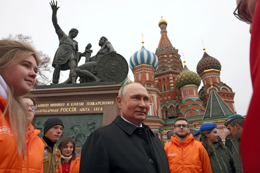 Russian President Vladimir Putin speaks with members of public associations, youth and volunteer organizations during a flower-laying ceremony at the monument to Kuzma Minin and Dmitry Pozharsky while marking Russia's Day of National Unity in Red Square in central Moscow, Russia, on November 4, 2022. (Sputnik/Mikhail Metzel/Pool via REUTERS)