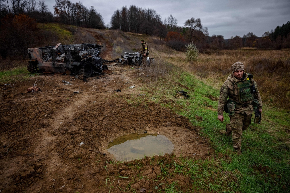 Ukrainian servicemen from the 127th brigade inspect destroyed Russian army's Armored Personal Carriers (APC) near the Ukrainian border with Russia in Kharkiv region, on November 5, 2022. (Photo by Dimitar DILKOFF / AFP)