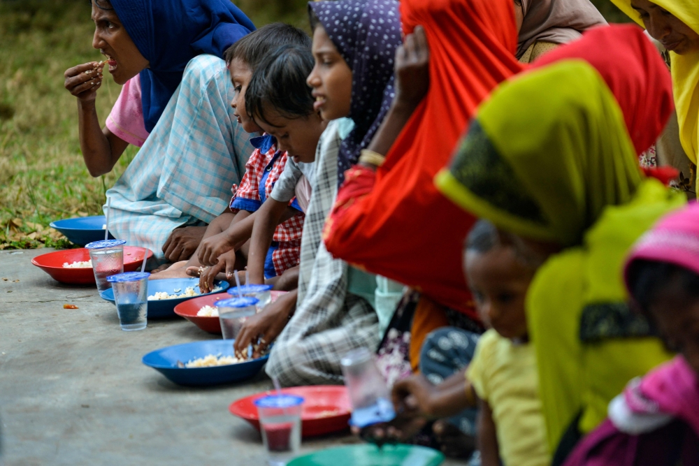 Rohingya refugees eat food in a temporary shelter following their arrival by boat in Laweueng, Aceh province on December 27, 2022. (Photo by Chaideer Mahyuddin / AFP)