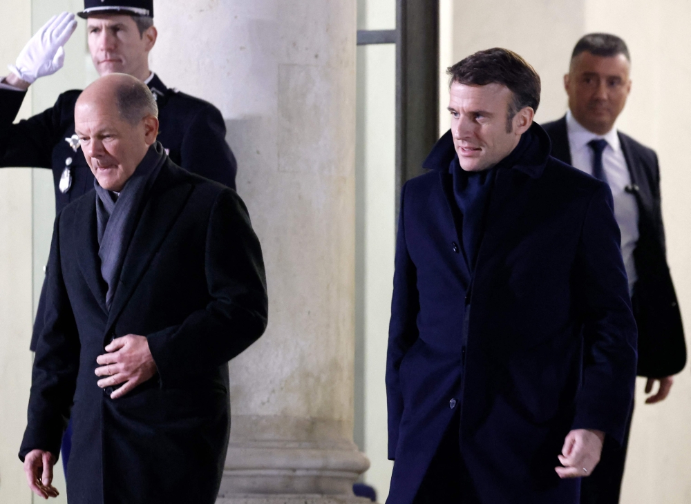French President Emmanuel Macron and German Chancellor Olaf Scholz leave the Elysee Palace prior to their dinner, as part of the celebration of the 60th anniversary of the signing of the Elysee Treaty, to seal reconciliation between France and West Germany, 18 years after the Second World War at the presidential Elysee Palace in Paris on January 22, 2023. (Photo by Ludovic MARIN / AFP)