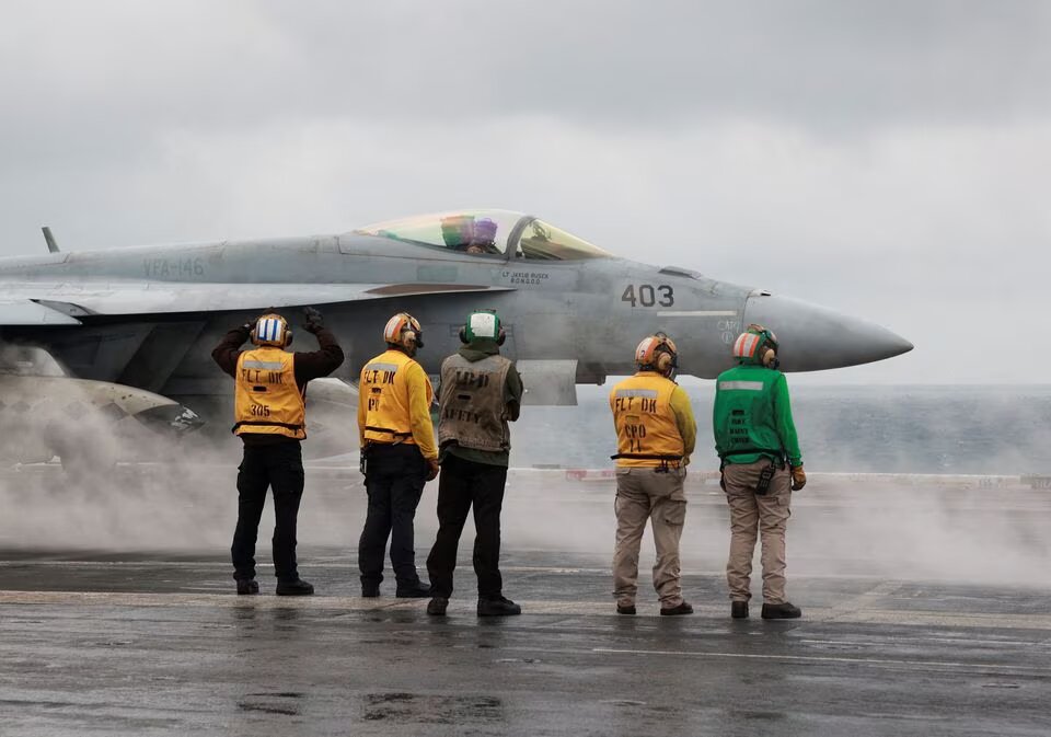 Crew members signal to a F/A-18E Super Hornet fighter jet preparing to take off for a routine flight on board the U.S. USS Nimitz aircraft carrier during a routine deployment to the South China Sea, Mid-Sea, on January 27, 2023. REUTERS/Joseph Campbell/File Photo
