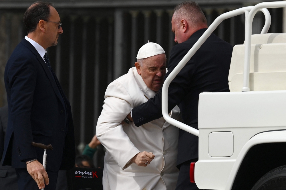 Pope Francis is helped get up the popemobile car as he leaves on March 29, 2023 at the end of the weekly general audience at St. Peter's square in The Vatican. (Photo by Vincenzo PINTO / AFP)