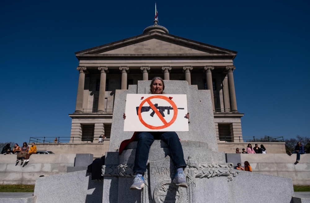 A protester sits with an anti-assault rifle sign near the Tennessee State Capitol to call for an end to gun violence and support stronger gun laws on March 30, 2023 in Nashville, Tennessee. (Photo by Seth Herald / GETTY IMAGES NORTH AMERICA / Getty Images via AFP)