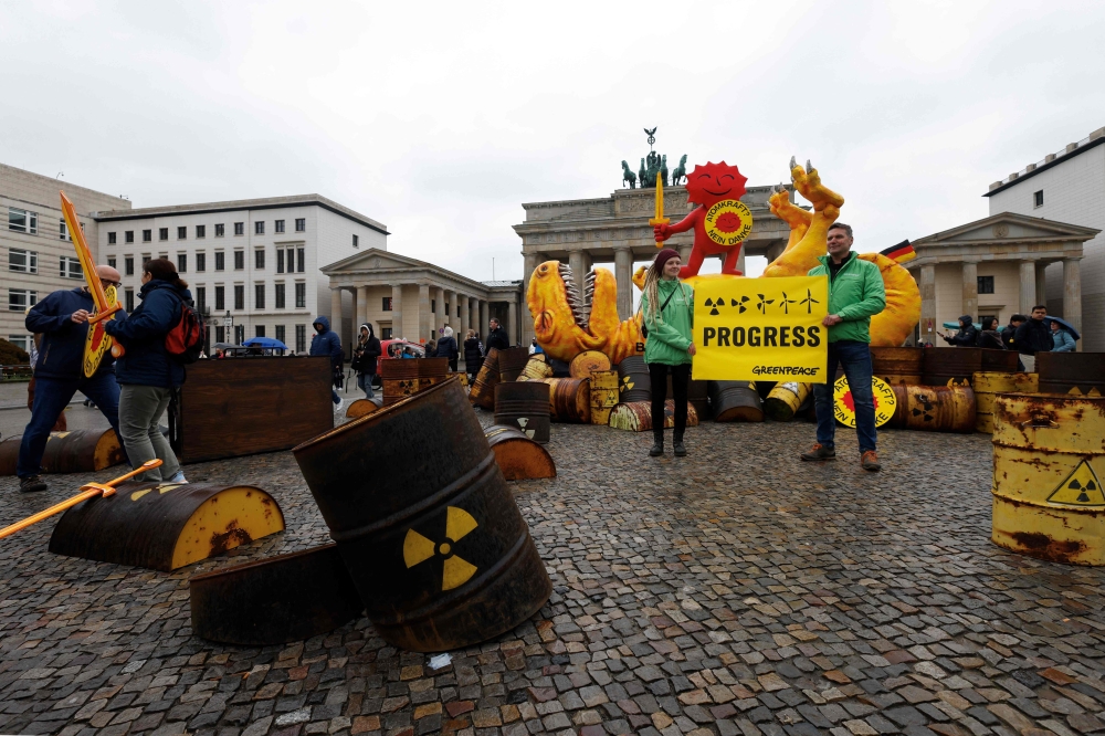 Activists of environmental organisation Greenpeace pose with a placard reading 'Progress' during a demonstration in front of the capital's landmark Brandenburg Gate in Berlin on April 15, 2023(Photo by Odd Andersen / AFP)
 