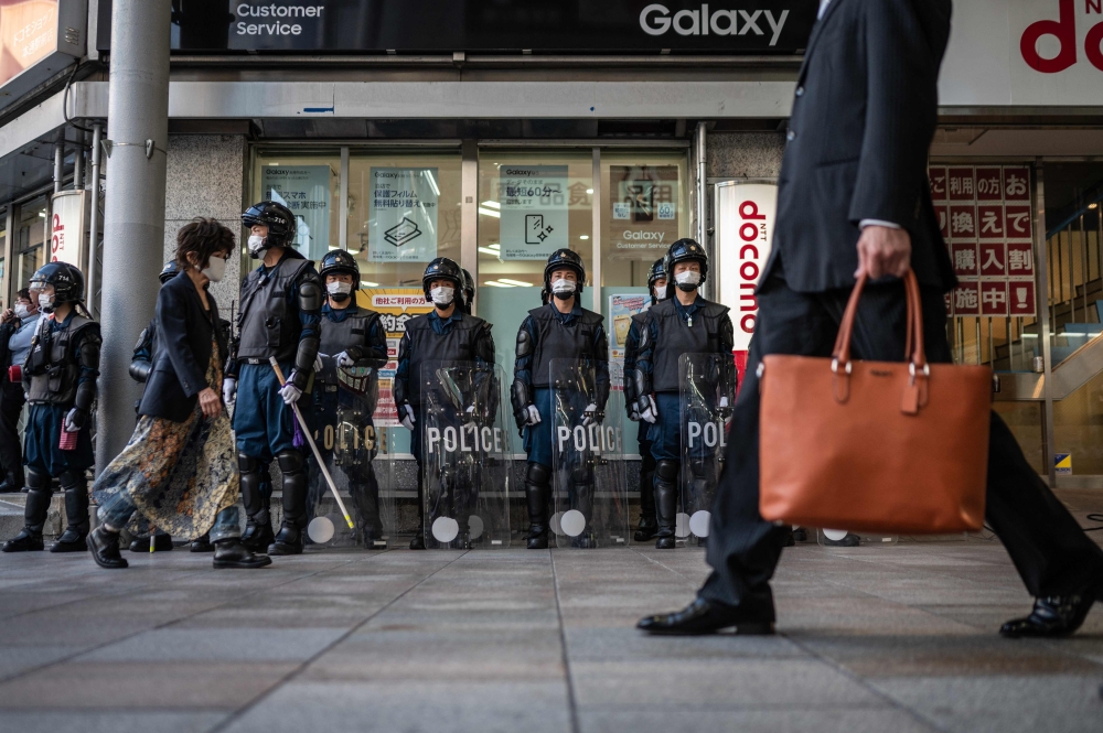 People walk past police officers standing guard near Peace Memorial Park in Hiroshima, ahead of the G7 Leaders' Summit, on May 17, 2023. Photo by Yuichi YAMAZAKI / AFP