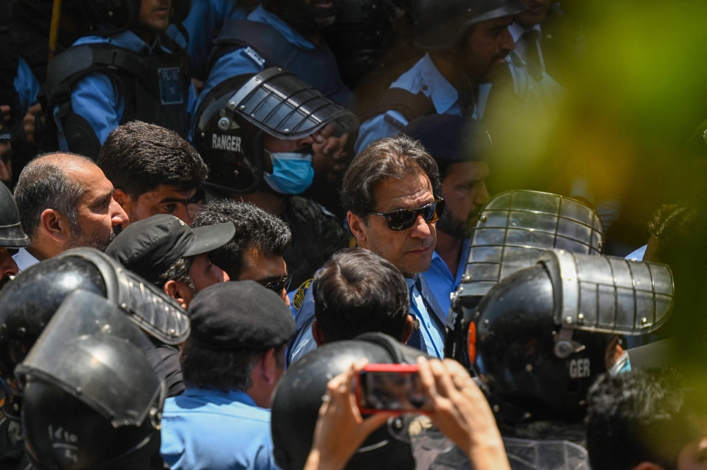 File photo: Policemen escort Pakistan's former Prime Minister Imran Khan (C) as he arrives at the high court in Islamabad on May 12, 2023. Photo by Aamir QURESHI / AFP


