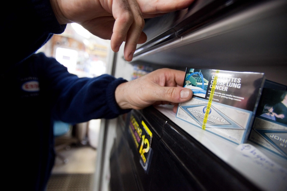 File Photo: A corner store owner in St. Thomas, Ontario, Canada, holds a package of cigarettes on March 12, 2012. Canada will soon require that health warnings be printed on individual cigarettes and cigars in a further crackdown on smoking, Canadian Addictions Minister Carolyn Bennett announced May 31, 2023. (Photo by Geoff Robins / AFP)
