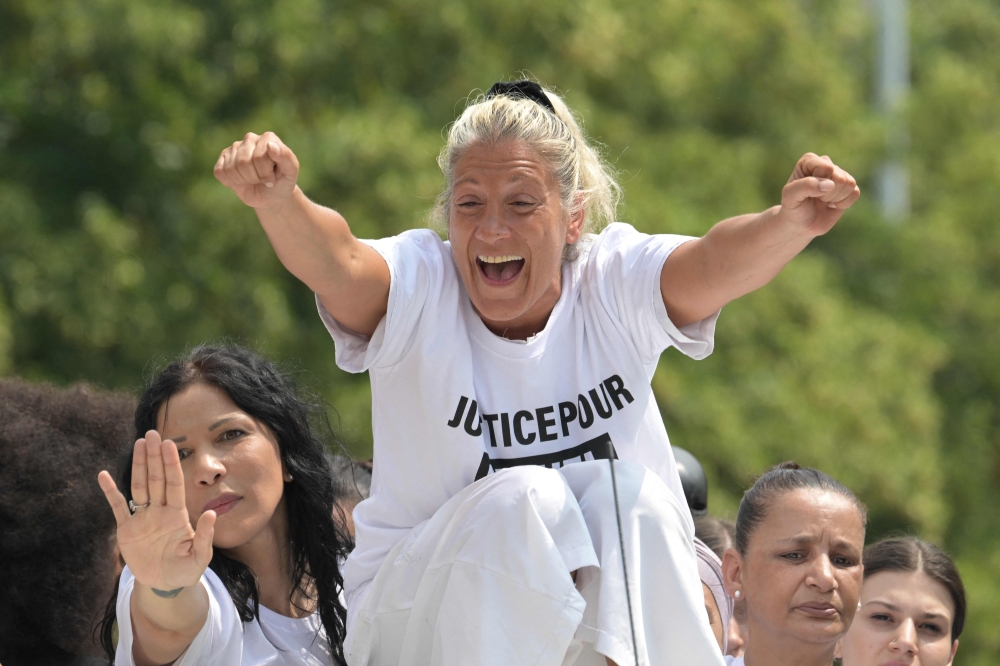 Mounia, the mother of Nahel, a teenage driver shot dead by a policeman, gestures as she sits atop a truck during a commemoration march for her son, in the Parisian suburb of Nanterre, on June 29, 2023. (Photo by Alain Jocard / AFP)