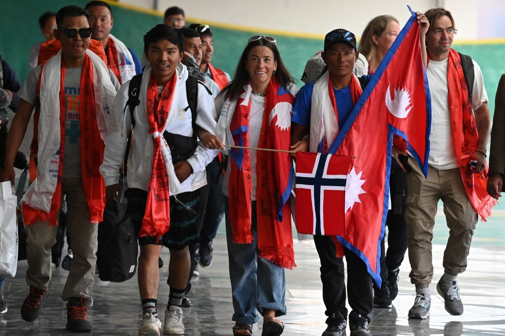 Norwegian climber Kristin Harila (C) and Nepali guide Tenjin Sherpa (C, right) arrive at the Tribhuvan International airport in Kathmandu on August 5, 2023. (Photo by Prakash Mathema / AFP)
