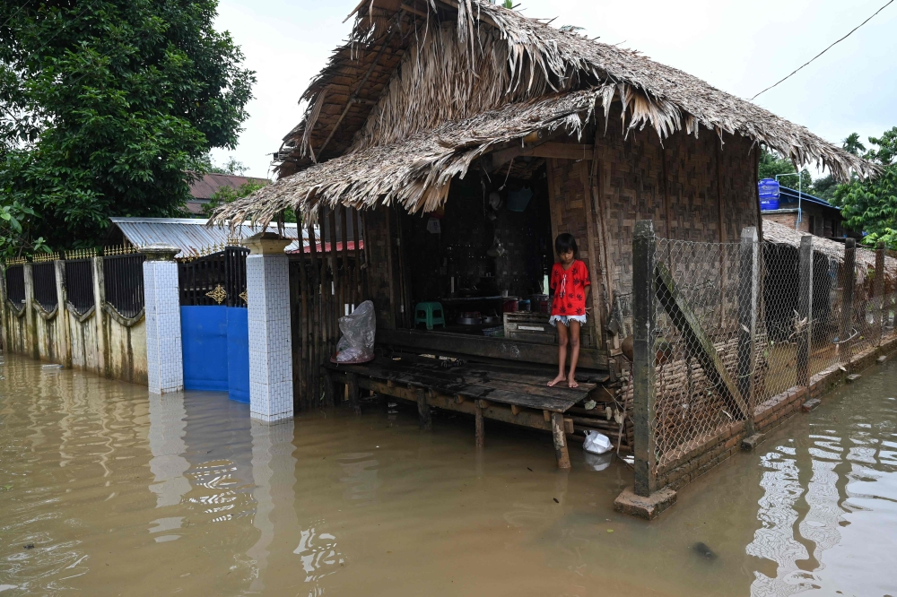 A girl stands outside her house above a flooded street in Bilin township, in Myanmar's Mon state, on August 11, 2023. (Photo by Sai Aung Main / AFP)