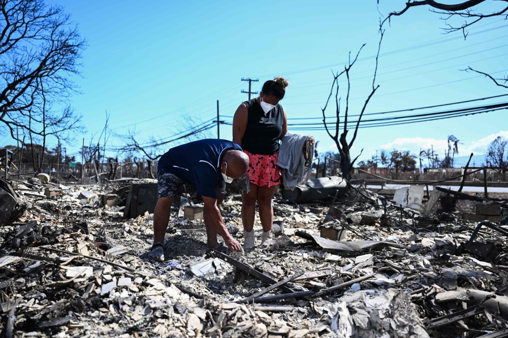 Davilynn Severson and Hano Ganer look for belongings through the ashes of their family痴 home in the aftermath of a wildfire in Lahaina, western Maui, Hawaii on August 11, 2023. (Photo by Patrick T. Fallon / AFP)
