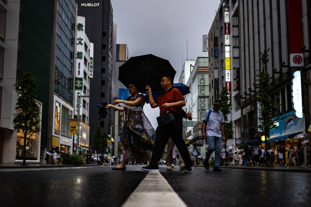 Pedestrians walk with their umbrellas in the rain in Ginza district of Tokyo on August 13, 2023, as Typhoon Lan heads for Japan's main island Honshu. Photo by Philip FONG / AFP