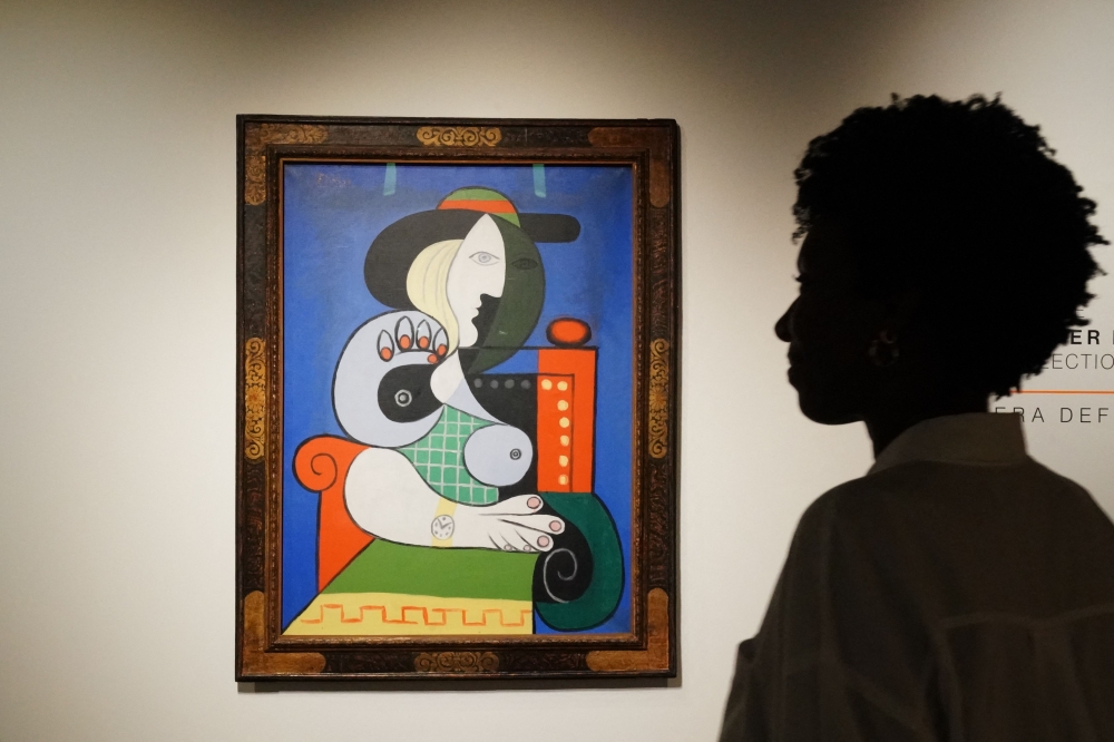 A visitor looks over Pablo Picasso’s painting Femme ل la montre, the painting will be auctioned in November as part of the Emily Fisher Landau Collection and is expected to fetch $120 million, pictured on display at Sotheby’s on September 13, 2023 in New York. (Photo by Bryan R. Smith / AFP)
