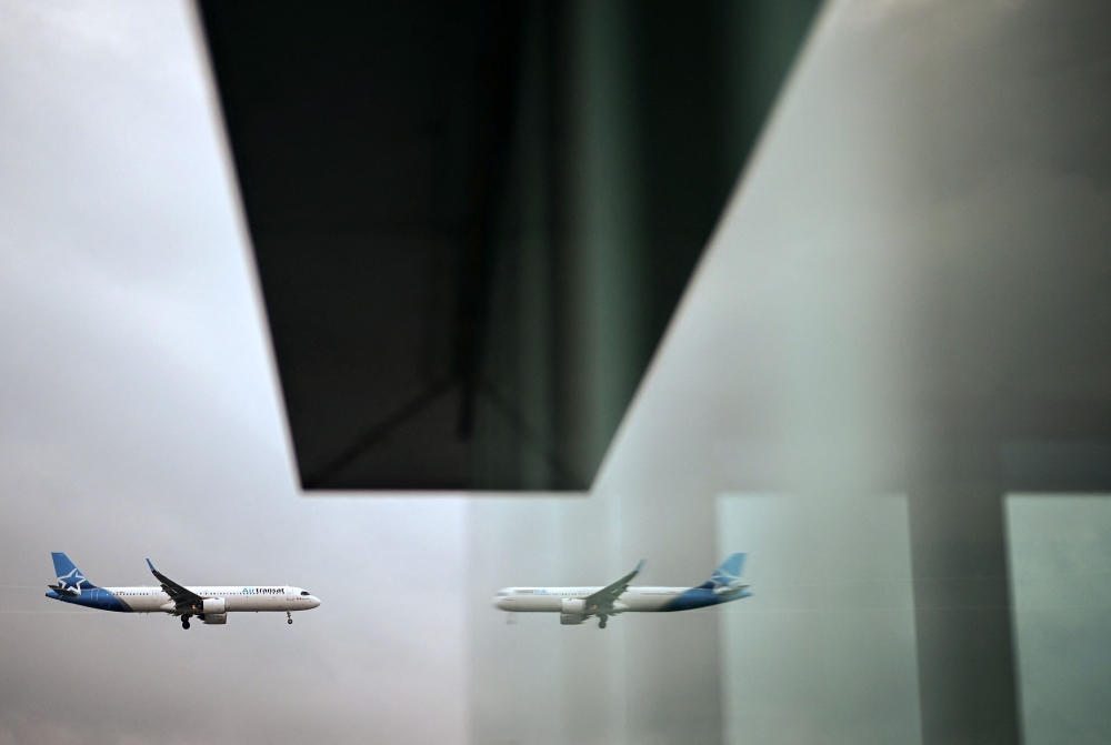 An Air Transat Airbus 321 aircraft is reflected in a window as it prepares to land at London Gatwick Airport, near Crawley, southern England, on September 26, 2023.  (Photo by Ben Stansall / AFP)