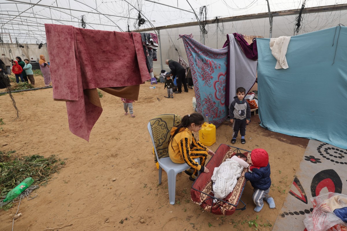 Palestinians, displaced by the Israeli bombardment of Khan Yunis, seek shelter inside an agricultural tent in Rafah in the southern Gaza Strip on December 21, 2023. Photo by MOHAMMED ABED / AFP