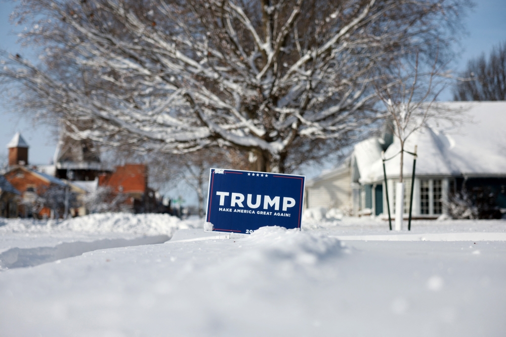 A campaign sign supporting Republican presidential candidate former President Donald Trump is stuck in the snow on January 15, 2024, in Pella, Iowa. (Photo by JOE RAEDLE / GETTY IMAGES NORTH AMERICA / Getty Images via AFP)
