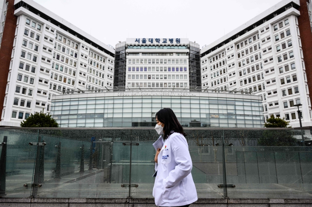 A medical worker walks past the Seoul National University Hospital in Seoul on February 21, 2024. Photo by ANTHONY WALLACE / AFP