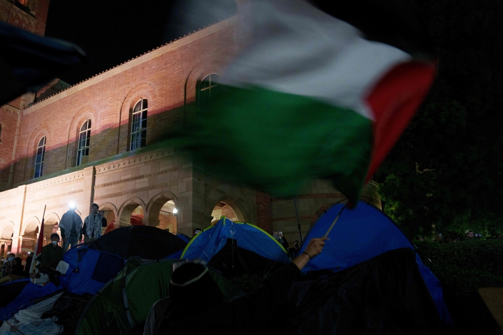 A Pro-Palestinian protestor waves a flag in an encampment at the University of California, Los Angeles (UCLA) campus on May 2, 2024 in Los Angeles, California. Photo by Eric Thayer / GETTY IMAGES NORTH AMERICA / Getty Images via AFP