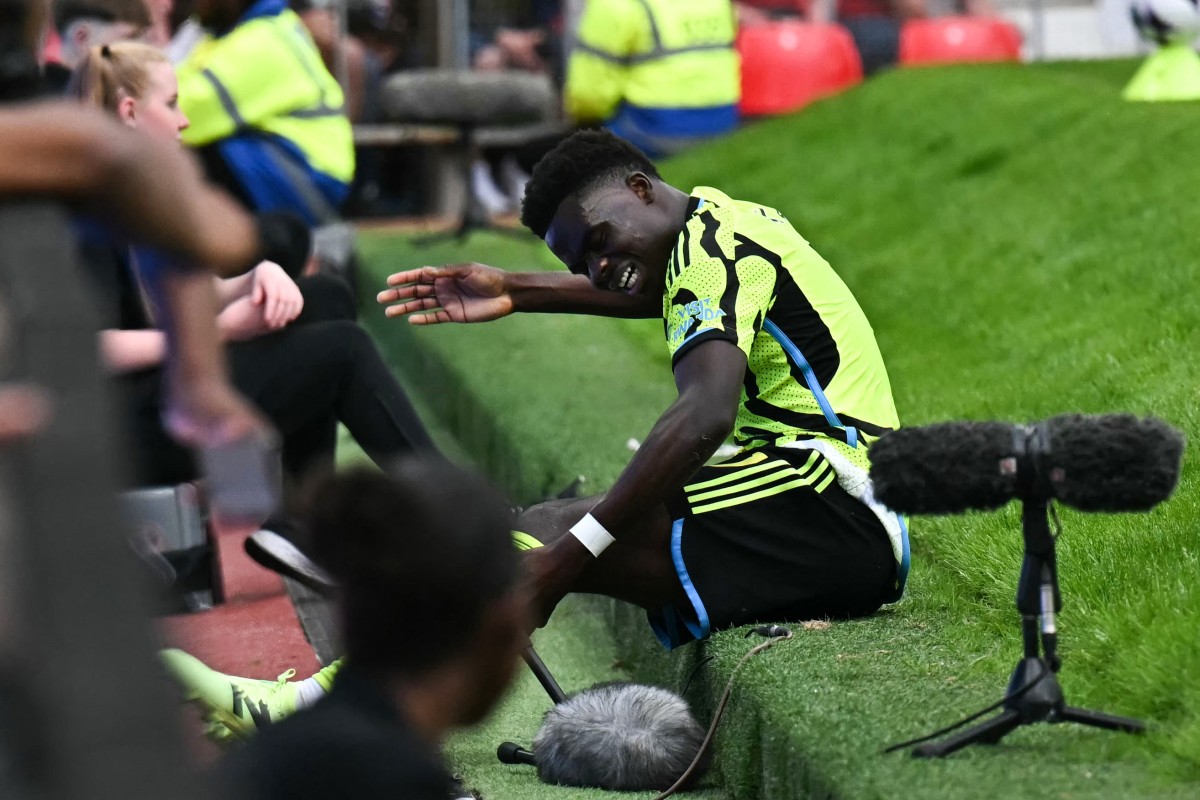 Arsenal's English midfielder #07 Bukayo Saka falls from the pitch during the English Premier League football match between Manchester United and Arsenal at Old Trafford in Manchester, north west England, on May 12, 2024. (Photo by Paul ELLIS / AFP)