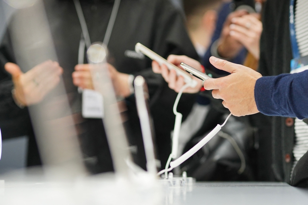 Attendees check out  mobile phones during the MWC (Mobile World Congress), the world's biggest mobile fair, in Barcelona on March 3, 2025. (Photo by Manaure Quintero / AFP)
