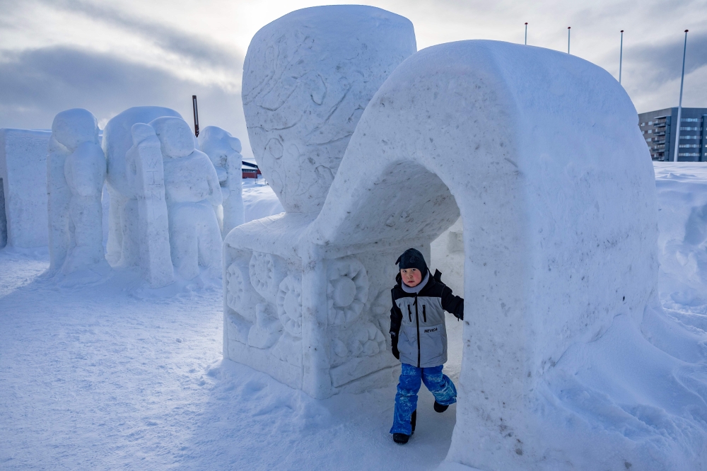 A young Greenlander plays among snow sculptures in Nuuk, Greenland, on March 4, 2025. (Photo by Odd Andersen / AFP)
