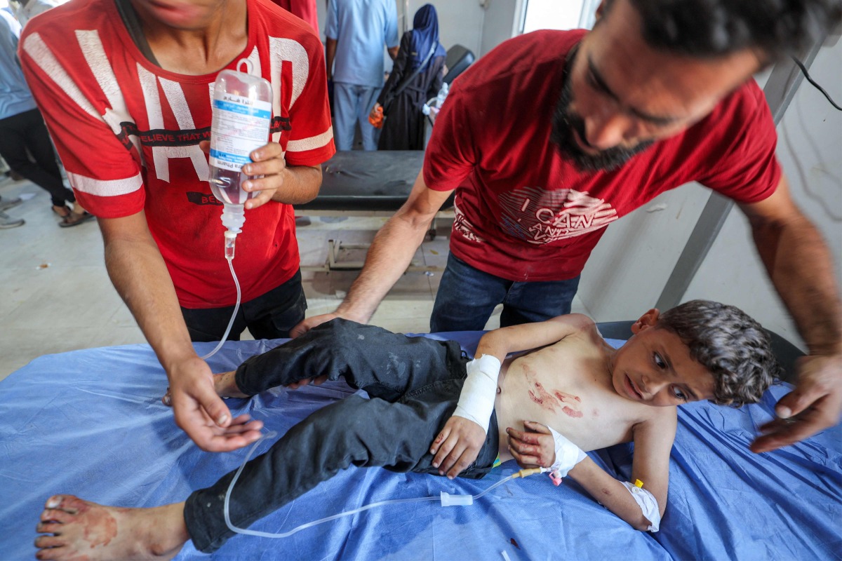 An injured boy is brought for treatment at Al-Awda Hospital in the Nuseirat camp for Palestinian refugees in the central Gaza Strip on July 16, 2025. (Photo by Eyad BABA / AFP)
