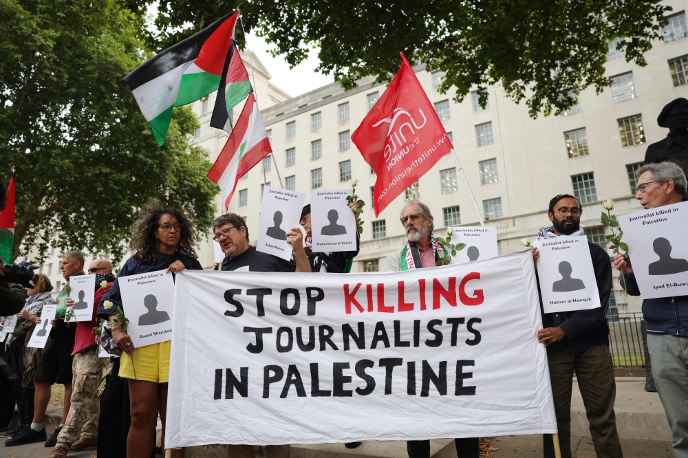 Protesters hold banners and Palestinian flags during a vigil for journalists killed in Gaza outside 10 Downing Street in central London on August 27, 2025. (Photo by Toby Shepheard / AFP)