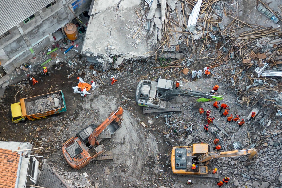 An aerial view shows rescuers searching for victims at the Al Khoziny Islamic boarding school in Sidoarjo, East Java, on October 5, 2025, after a multi-story building at the school collapsed during prayers. (Photo by Dicky Bisinglasi / AFP)