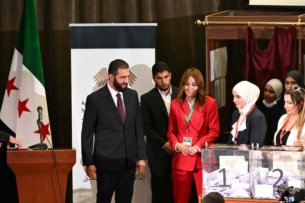 Syria's interim President Ahmed al-Sharaa (left) visits the poling station where members of Syrian local committees have been casting their votes in the country's selection process to designate an interim parliament, in Damascus on October 5, 2025. (Photo by Louai Beshara / AFP)
