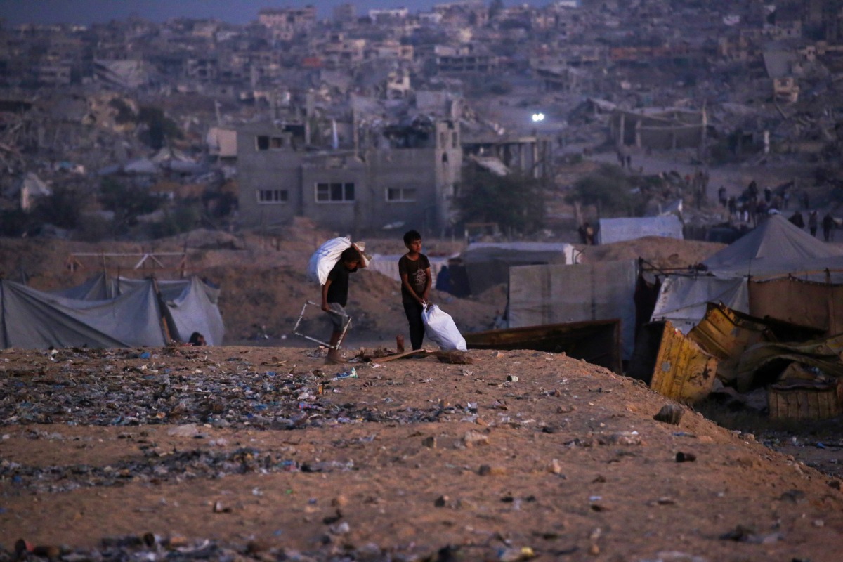 Palestinian children carry salvaged items in Khan Yunis, in the southern Gaza Strip on October 25, 2025. Photo by Bashar TALEB / AFP