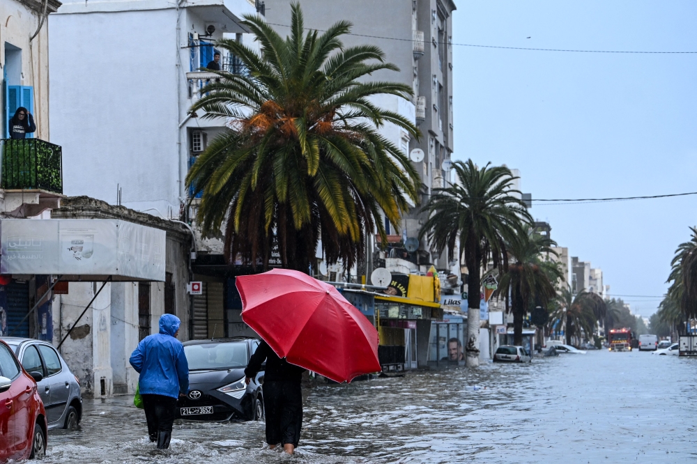 Residents make their way through flood waters, in La Goulette near the capital Tunis, on Januray 20, 2026. (Photo by FethiI Belaid / AFP)
 