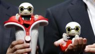 In this Sept. 27, 2016 photo, Toyota Motor Corp. SMO Moritaka Yoshida, right, and Fuminori Kataoka, project general manager from Toyota Motor Corp., pose for photographers with compact sized humanoid communication robots, Kirobo Mini.(AP Photo/Shizuo Kam)