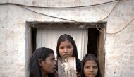 File photo of the daughters of Aasia Bibi with an image of their mother, standing outside their residence. Reuters
