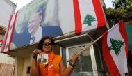 A supporter of Lebanese presidential candidate Michel Aoun holds his portrait and the Lebanese flag ahead of a parliament session expected to elect the ex-general as president and end a political stalemate of more than two years, as they gather in Jdeidah