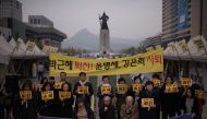 Protesters hold placards reading 