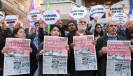 Protesters hold copies of the latest edition of the Turkish daily newspaper 