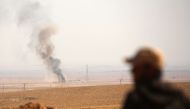 Smoke billows in the background as a member of the Syrian Democratic Forces (SDF), a US-backed Kurdish-Arab alliance, looks on in the village of Tal Aaj, 5 kilometre from the Syrian town of Ain Issa, some 50 kilometres (30 miles) north of Raqa, on Novembe