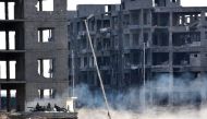 Syrian pro-government forces drive past heavily damaged buildings in Aleppo's 1070 district on November 8, 2016, after troops seized it from rebel fighters.  AFP / GEORGES OURFALIAN
