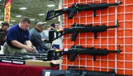 Potential buyers try out guns which are displayed on an exhibitor’s table during the Nation’s Gun Show in Virginia. 