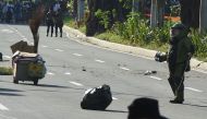 A member of police bomb disposal unit (R) holding a water bomb disruptor, walks towards the site where a suspicious package was found, for detonation along Roxas boulevard near the US embassy in Manila on November 28, 2016. AFP / TED ALJIBE